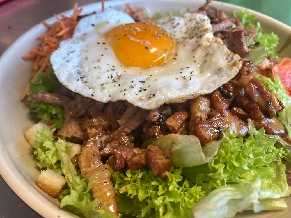 Grande salade garnie, surmontée d'un œuf au plat