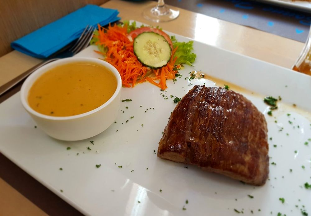 Pièce de viande grillée, sa sauce et ses crudités